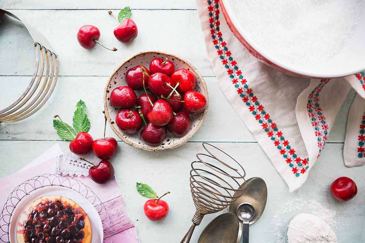 Bowl of cherries surrounded by cooking utensils