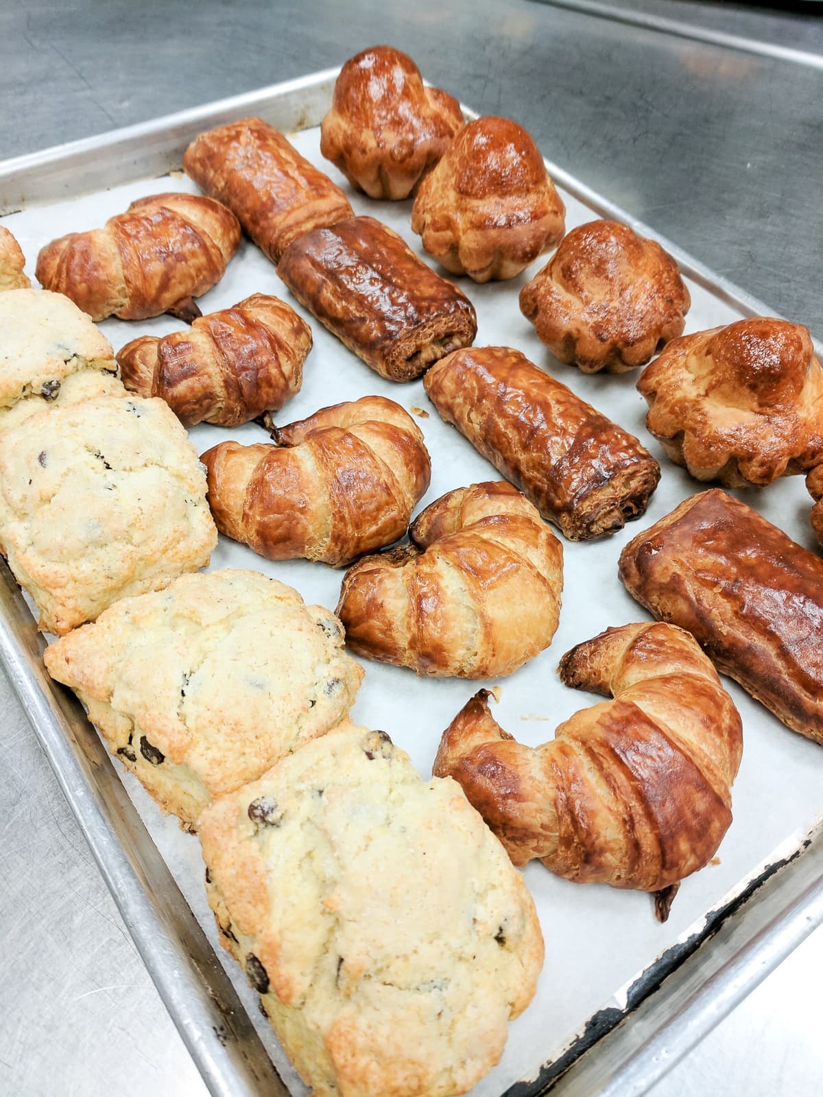 Scones, croissants, pain au chocolate, and brioche a tete on a sheet tray 