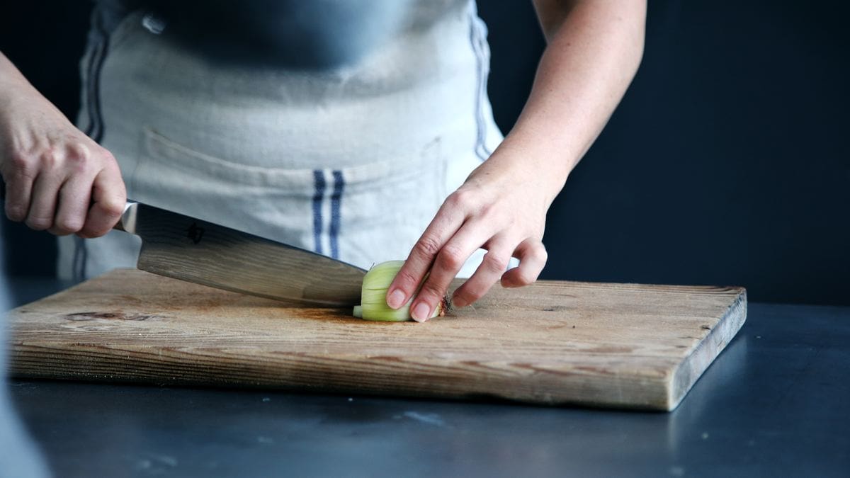 Person cutting an onion on a cutting board 