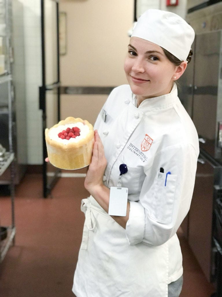 Leslie Jeon in chef's whites holding a charlotte russe cake