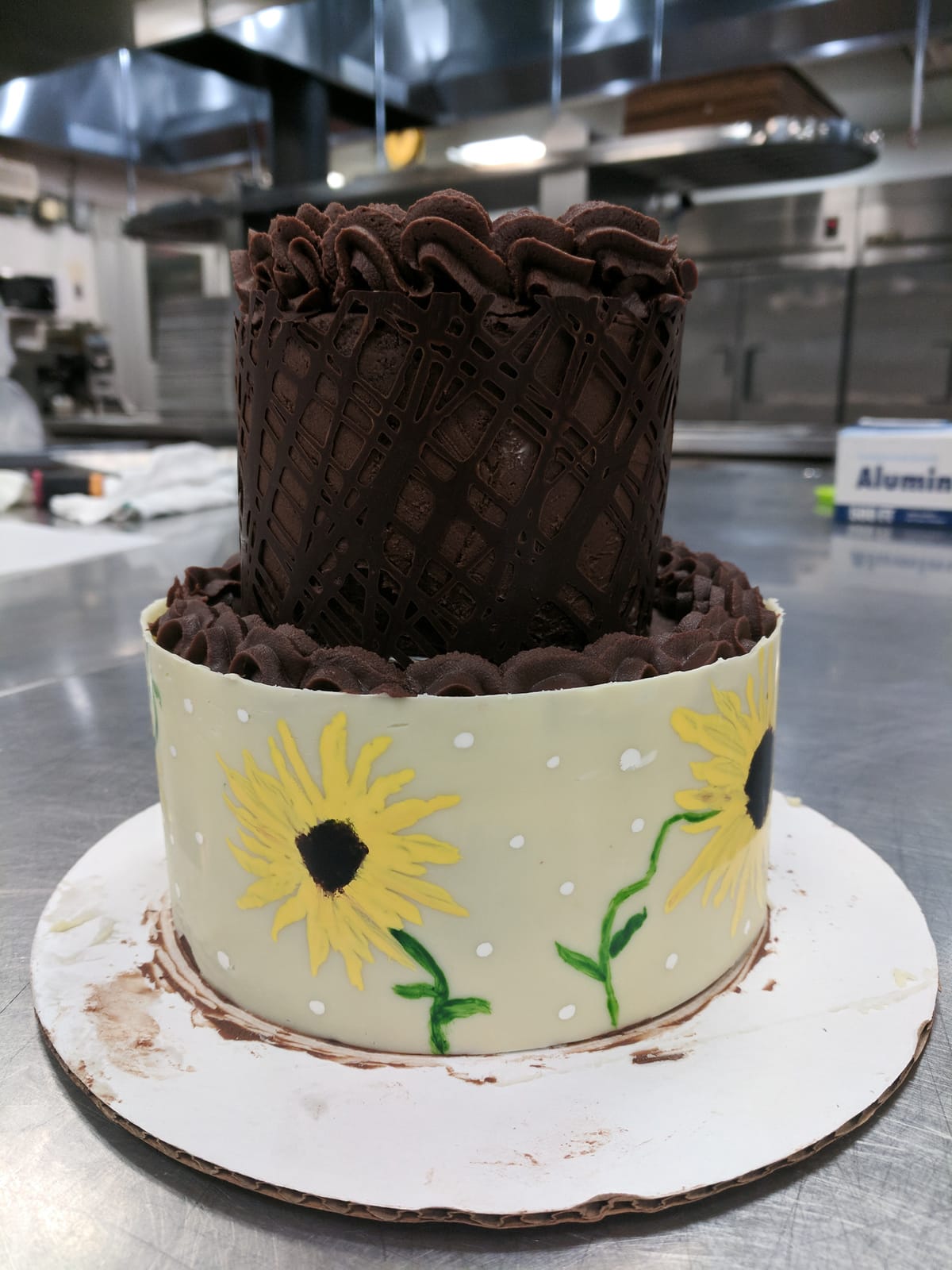 Two-tiered cake with a chocolate collar and sunflower design