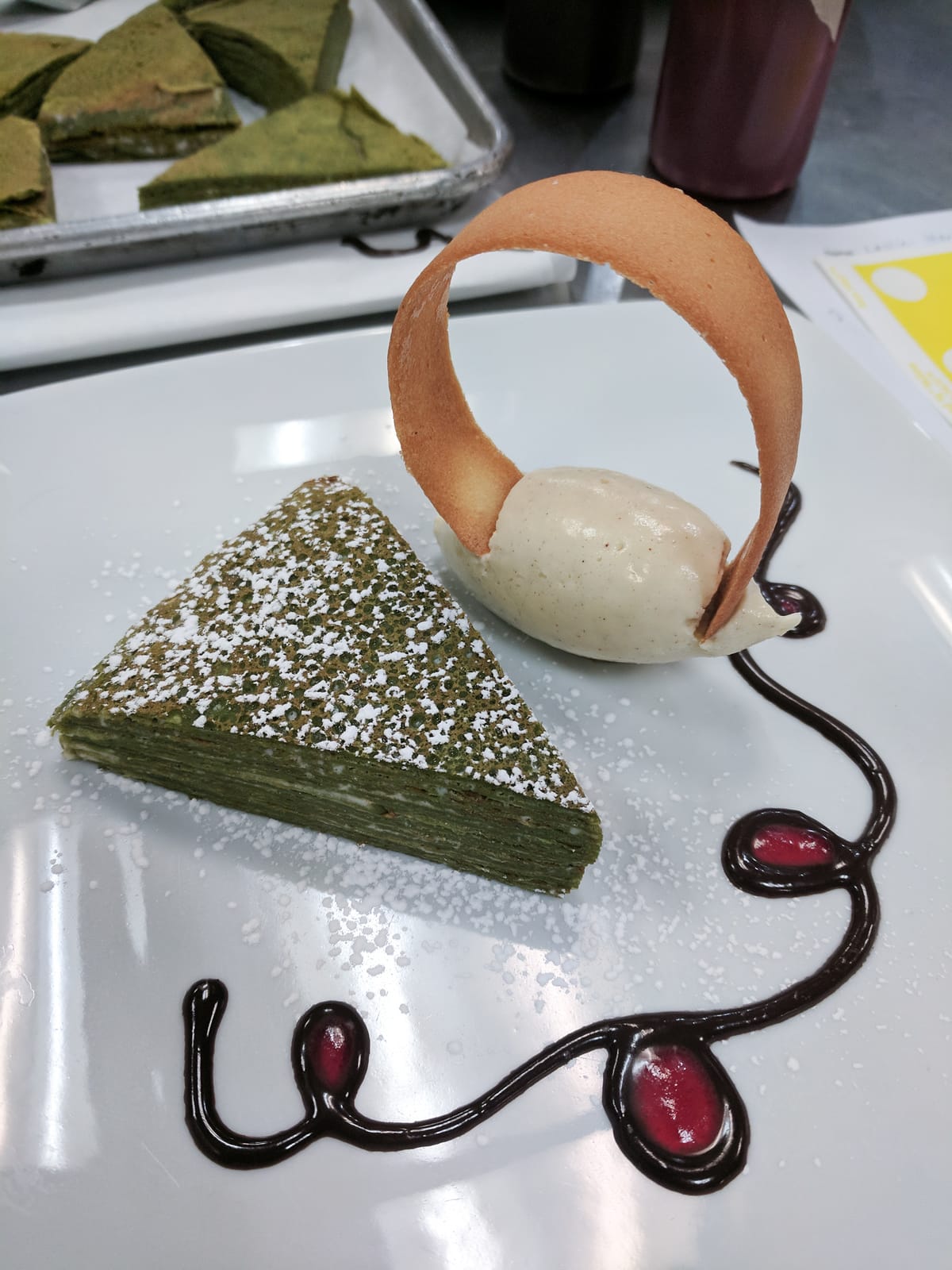 Matcha crepe cake with cinnamon and cardamom ice cream, chocolate sauce, and raspberry coulis