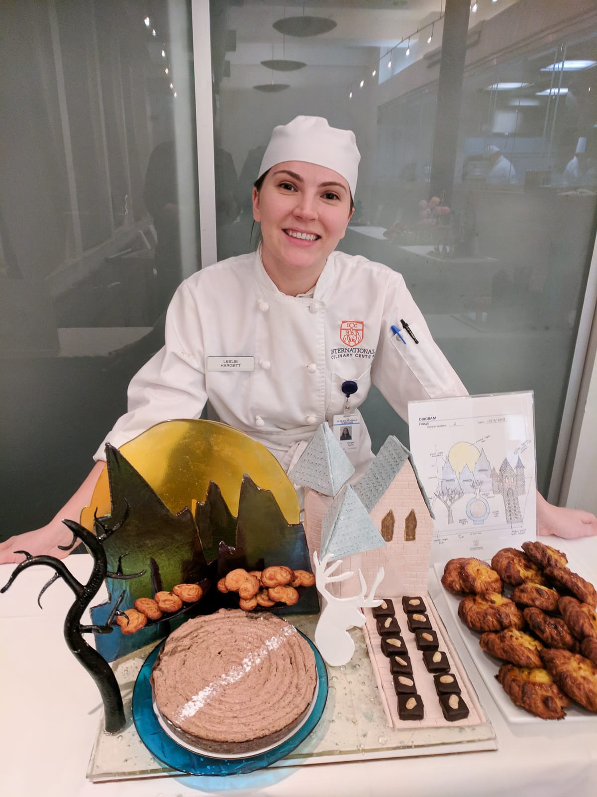 Girl in chef's uniform standing in front of showpiece