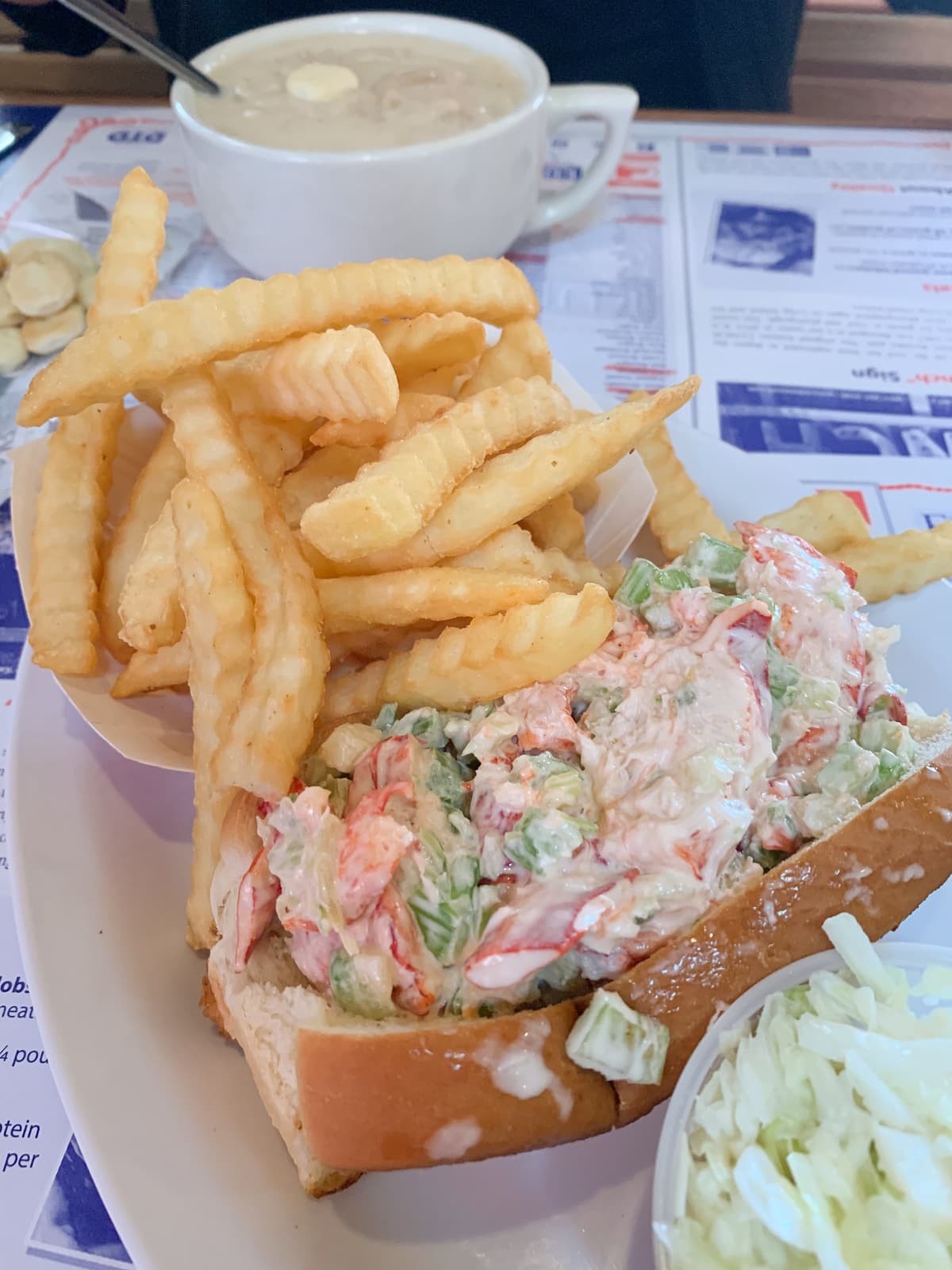 Lobster roll next to lots of crinkly fries 