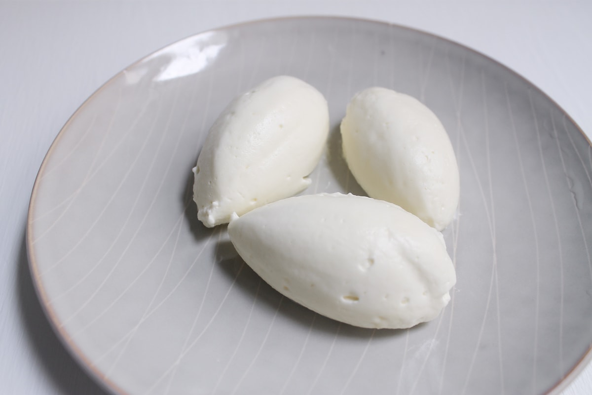 Close-up shot of three quenelles of whipped cream on a plate