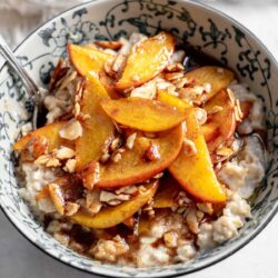 Bowl of oatmeal topped with peaches and almonds
