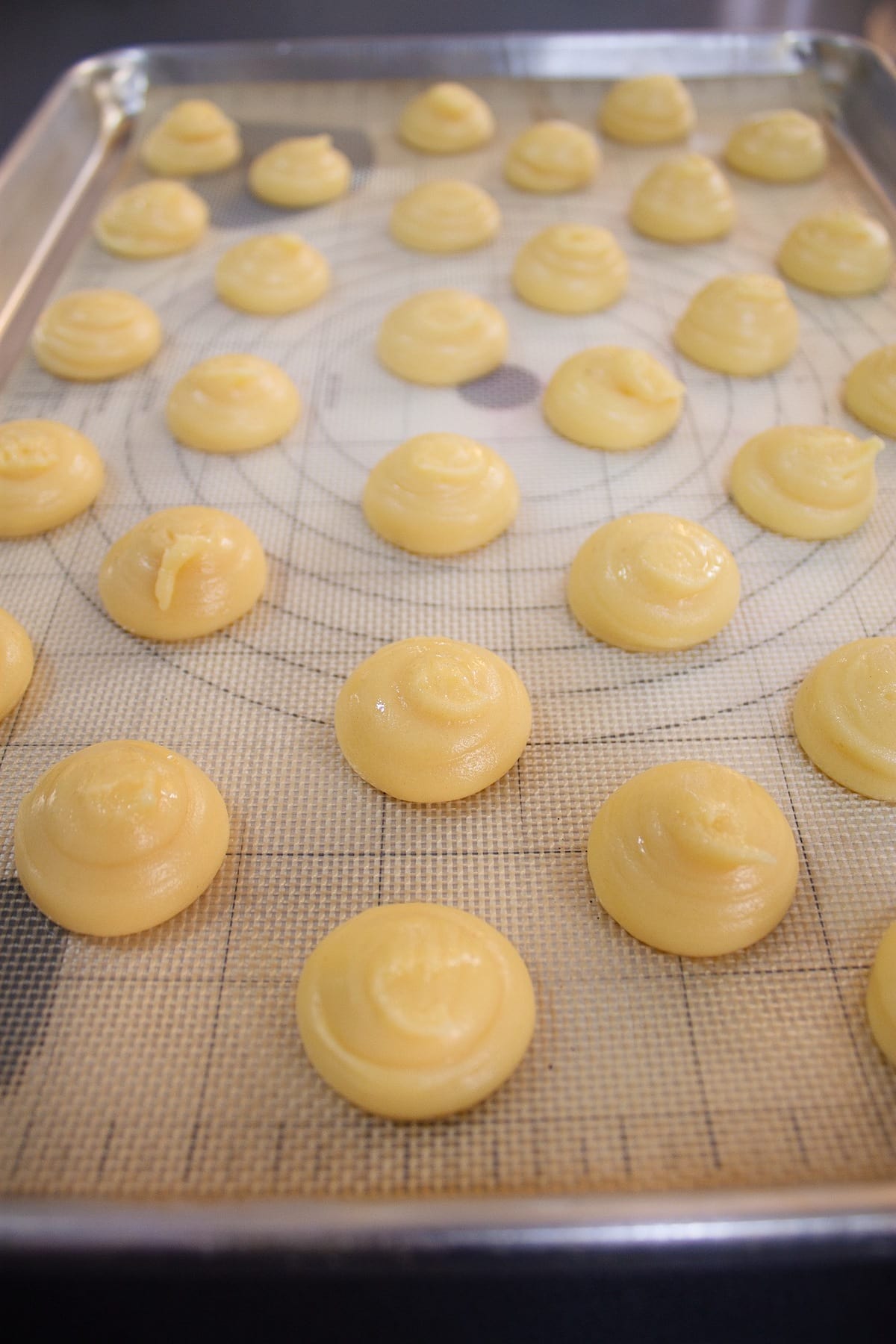 Choux pastry rounds piped onto a sheet tray