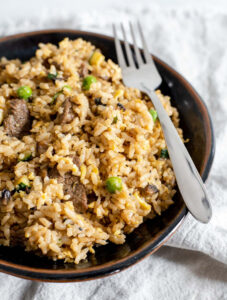 Bowl of beef fried rice with a fork resting on top