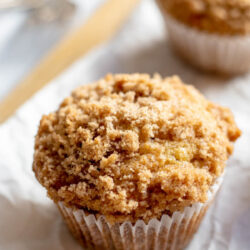 Banana crumb muffins on a cutting board with parchment paper with text that reads 'Banana crumb muffins'