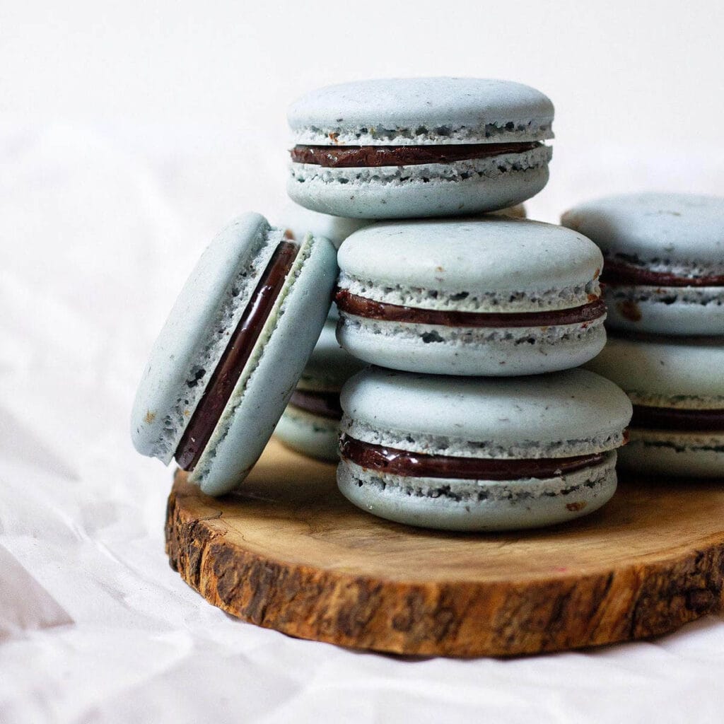 Stack of earl grey macarons on top of a wooden coaster