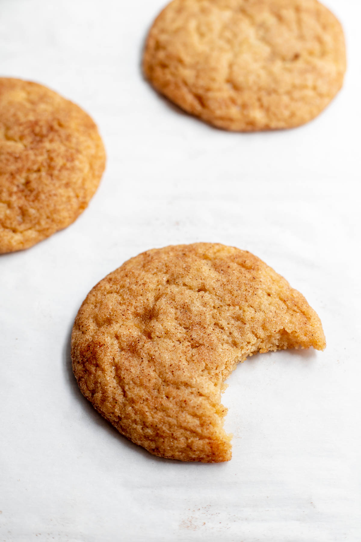 Three snickerdoodle cookies with a bite taken out of one of them 