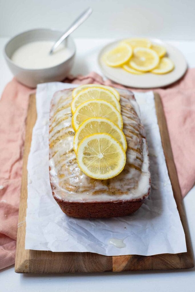 Earl grey and lemon loaf cake topped with lemons on top of a cutting board