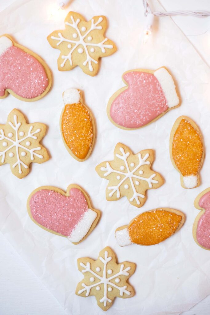 Overhead shot of orange, pink, and white Christmas cookies on parchment paper