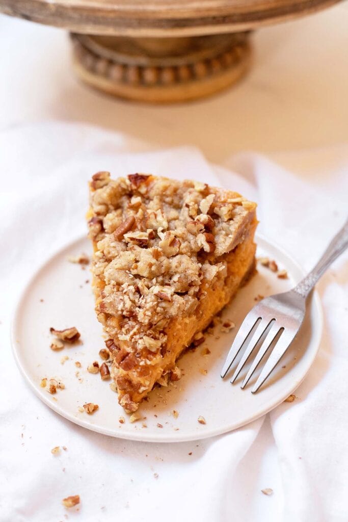 Slice of sweet potato casserole cheesecake on a plate with a fork next to it 