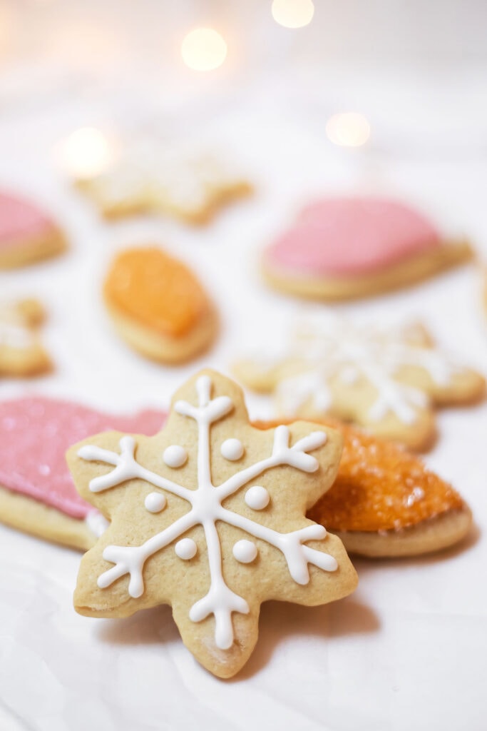 Pink, orange, and white sugar cookies on parchment paper with a white snowflake as the focal point