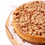 Uncut sweet potato casserole cheesecake on top of a cake stand