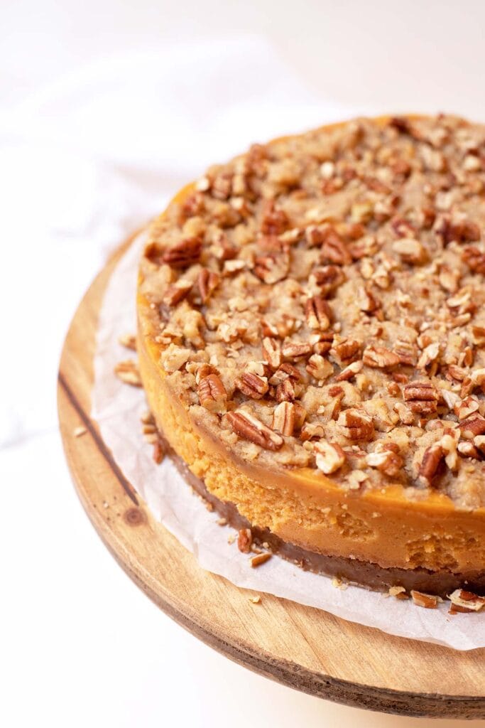 Uncut sweet potato casserole cheesecake on top of a cake stand