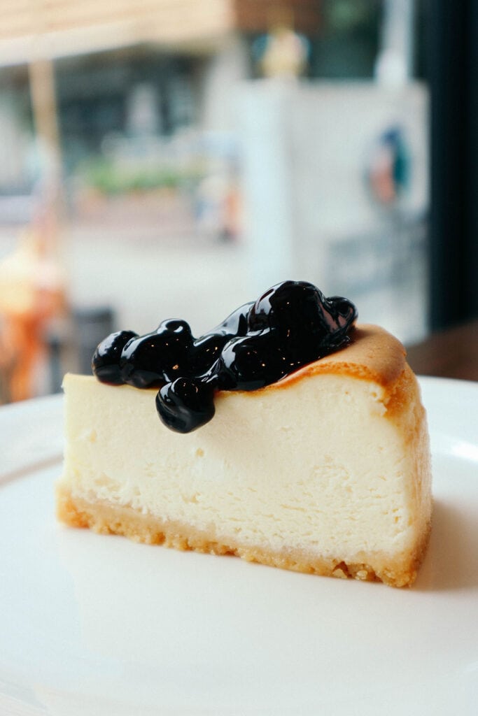 Slice of blueberry cheesecake in front of a window