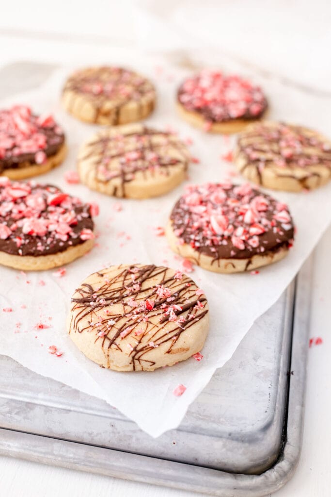 Chocolate peppermint shortbread cookies lying on parchment paper on an overturned baking sheet