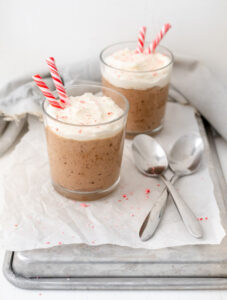 Two glasses of chocolate mousse topped with whipped cream and candy canes and text that reads 'Peppermint Chocolate Mousse'