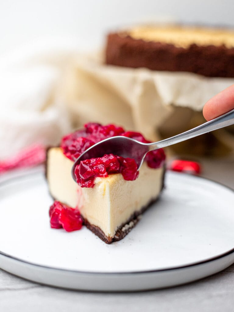 Spoon cutting into a slice of raspberry cheesecake