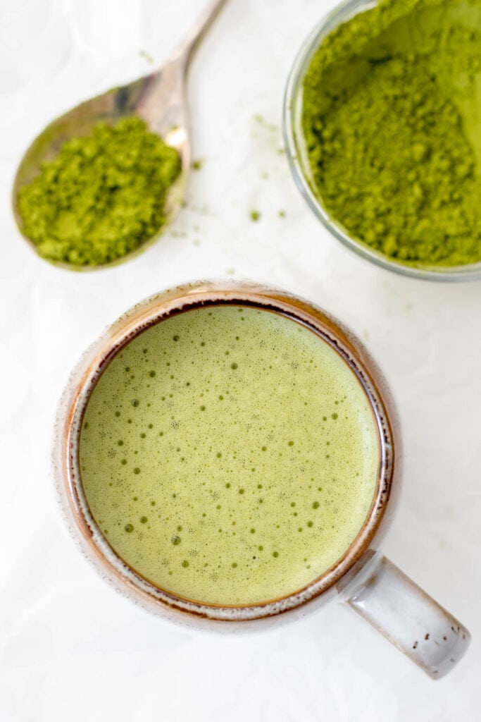 Overhead shot of matcha powder and an oat milk matcha latte 