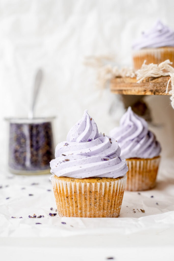 Two earl grey lavender cupcakes in front of a container of lavender