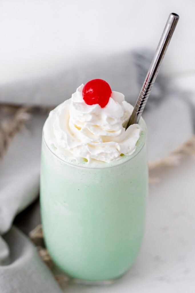 Close-up shot of shamrock shake topped with whipped cream and a cherry
