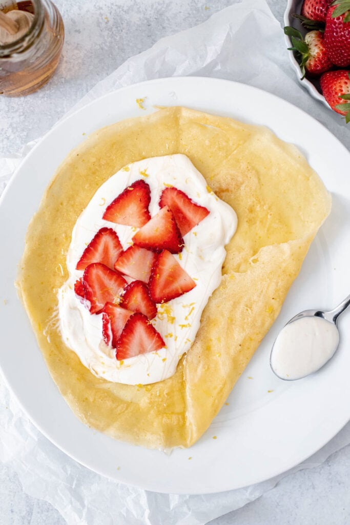 Overhead shot of crepe open topped with whipped ricotta and strawberries