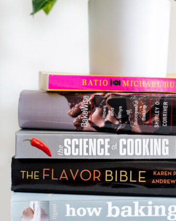 Stack of baking books resting underneath a plant