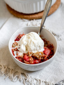Bowl of strawberry cardamom crisp with ice cream