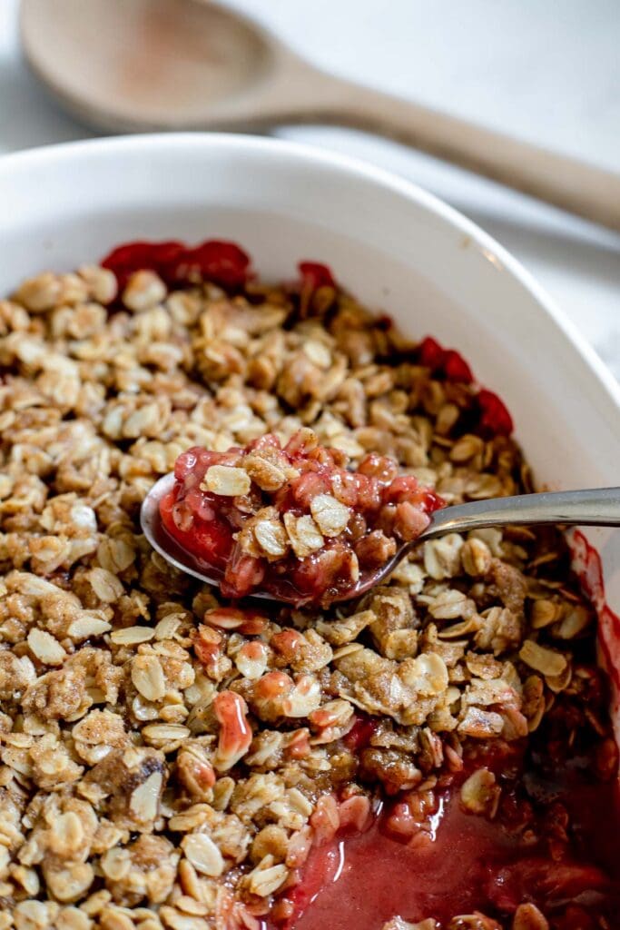 Spoonful of strawberry cardamom crisp resting on top of the rest of the container