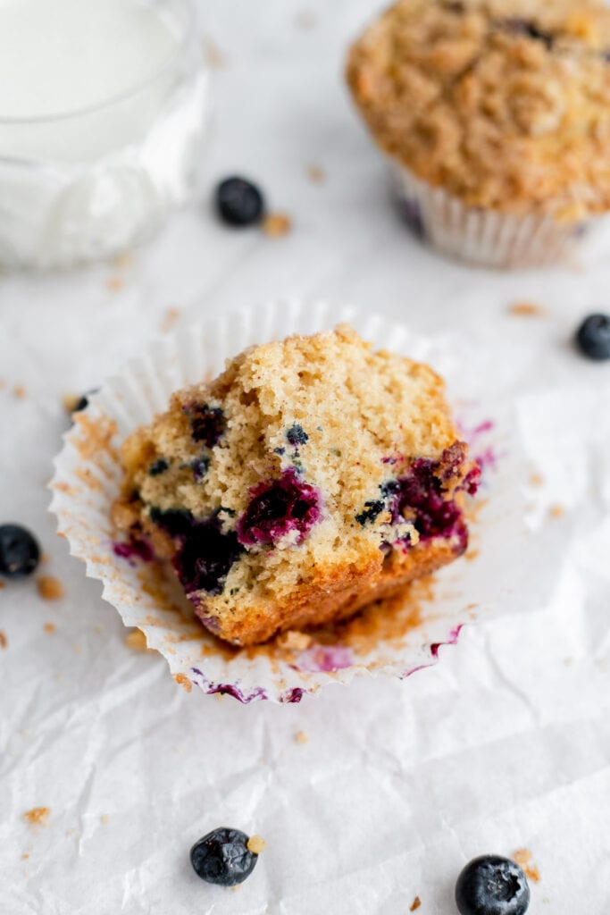 Blueberry muffin that's been bitten into resting on a muffin liner