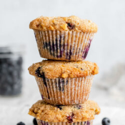 Stack of blueberry muffins in front of a jar of blueberries with text that reads 'Blueberry muffins'