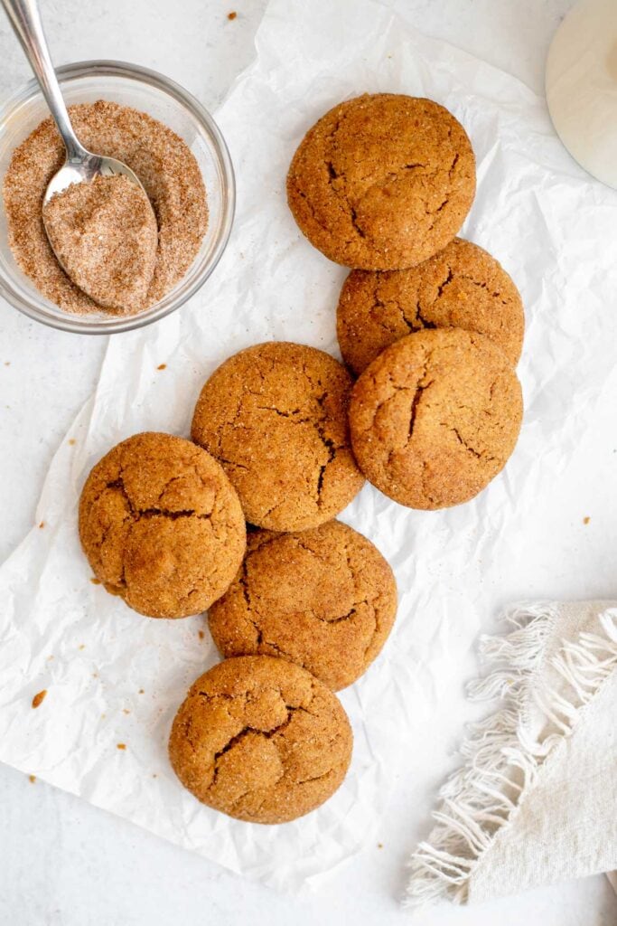 Overhead shot of vegan gingerdoodles on parchment paper next to a sugar mixture 