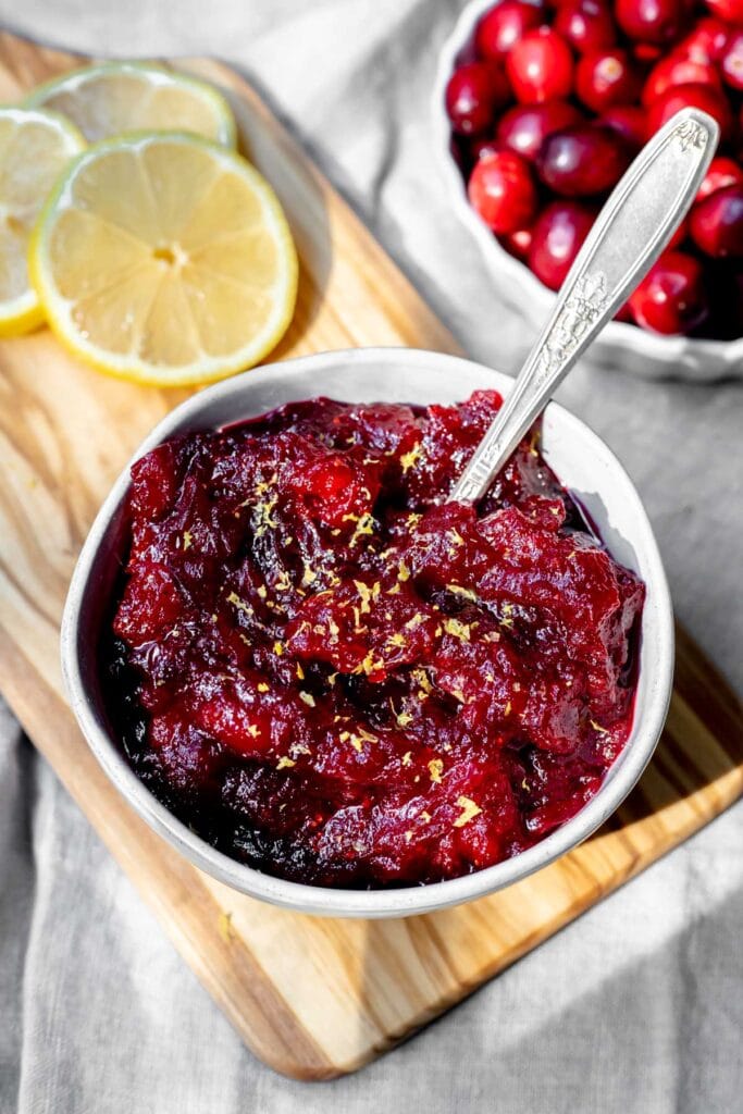 Bowl of cranberry sauce in front of lemons and a bowl of cranberries