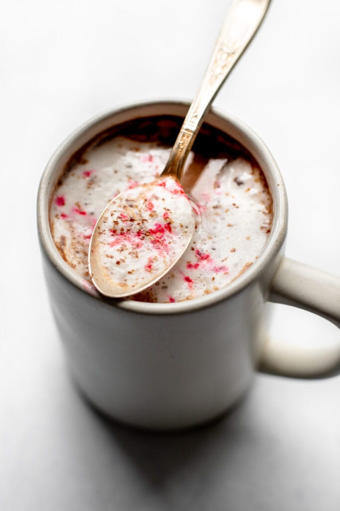 Mug of peppermint hot chocolate with a spoon resting on top of it