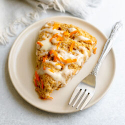Carrot cake scone on a plate next to a fork and napkin