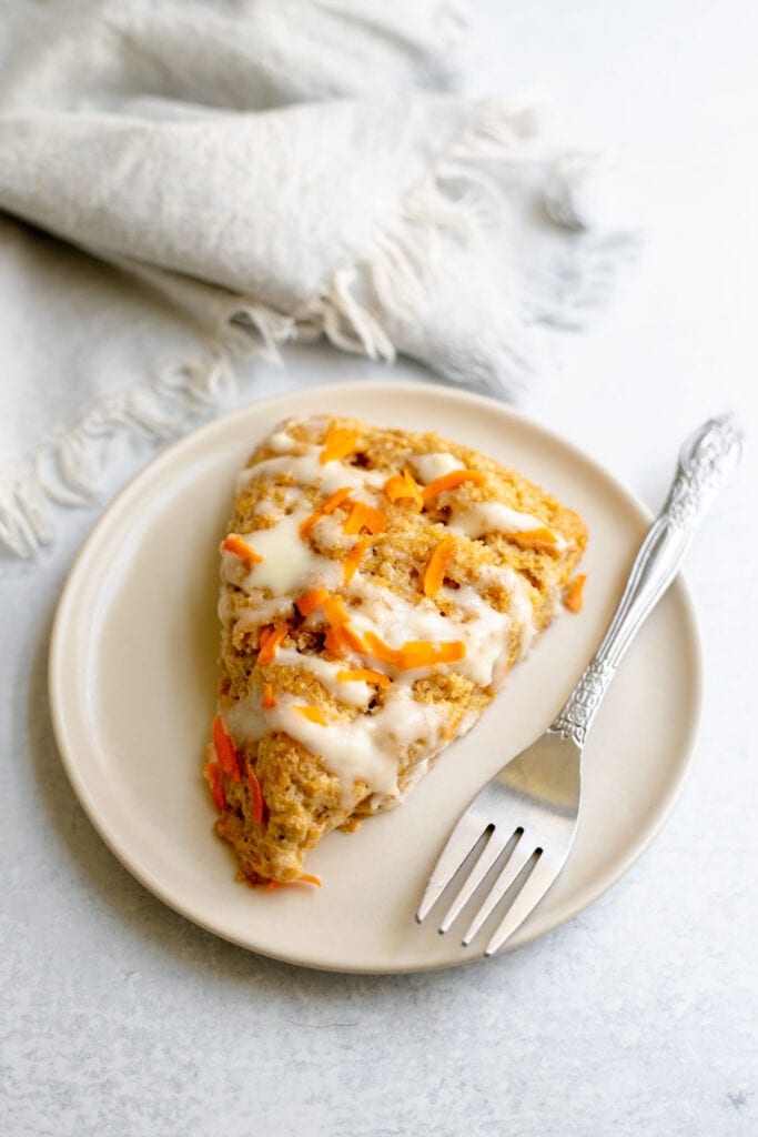 Carrot cake scone on a plate next to a fork and napkin 