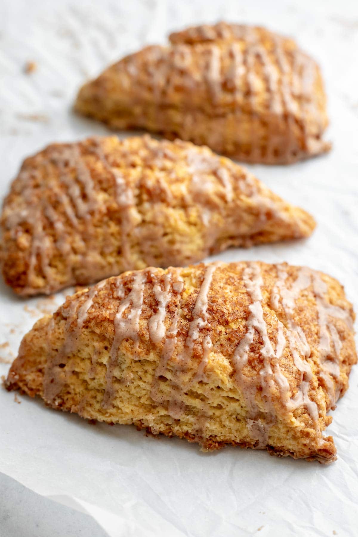 Three snickerdoodle scones in a line on parchment paper