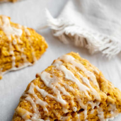 Pumpkin scones on parchment paper in front of a napkin with text that reads 'easy pumpkin scones'