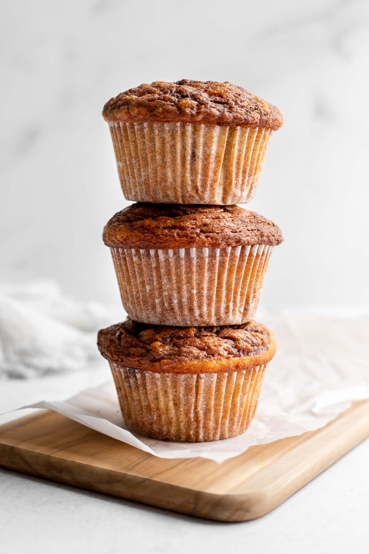 Stack of three banana nutella muffins on a cutting board