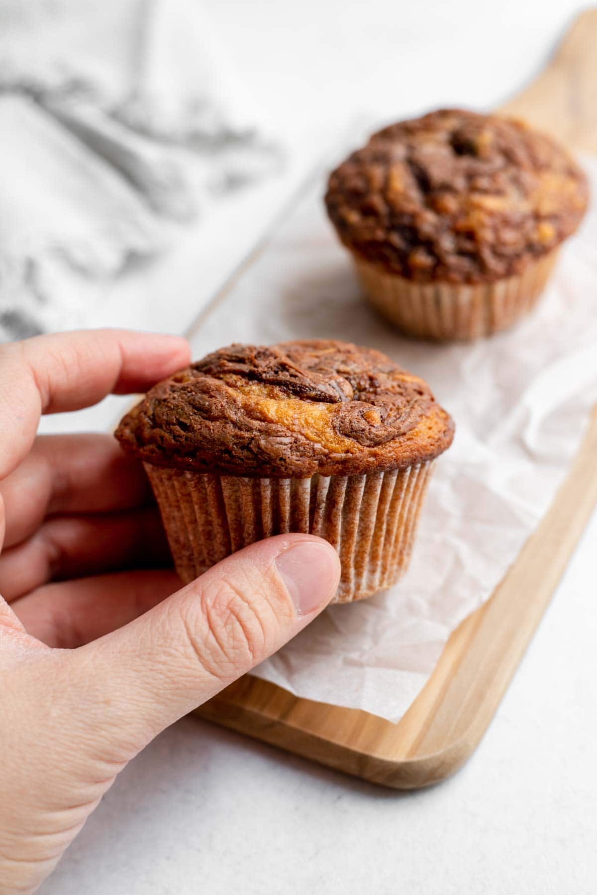 Hand holding a banana nutella muffin on a cutting board 