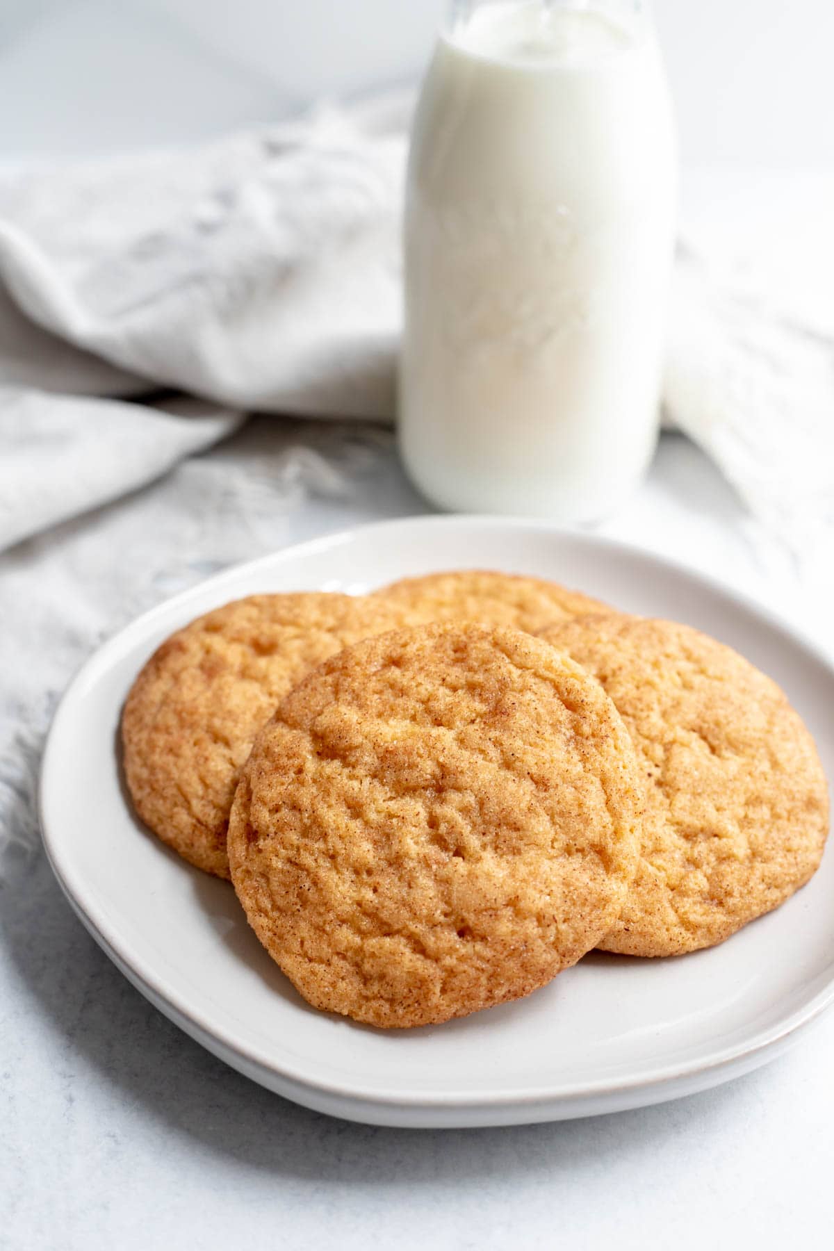 Plate of vegan snickerdoodles in front of a glass of milk 