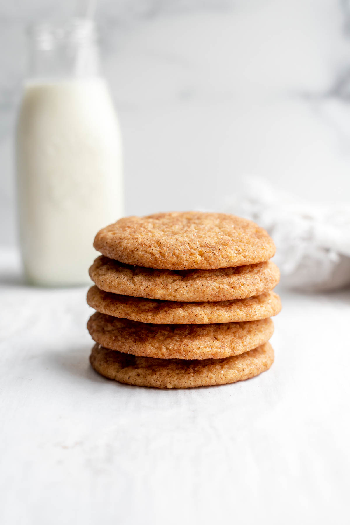 Stack of vegan snickerdoodles in front of a glass of milk